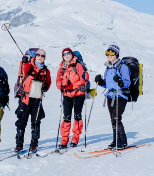 Fire personer i vinterklær med ski og staver 