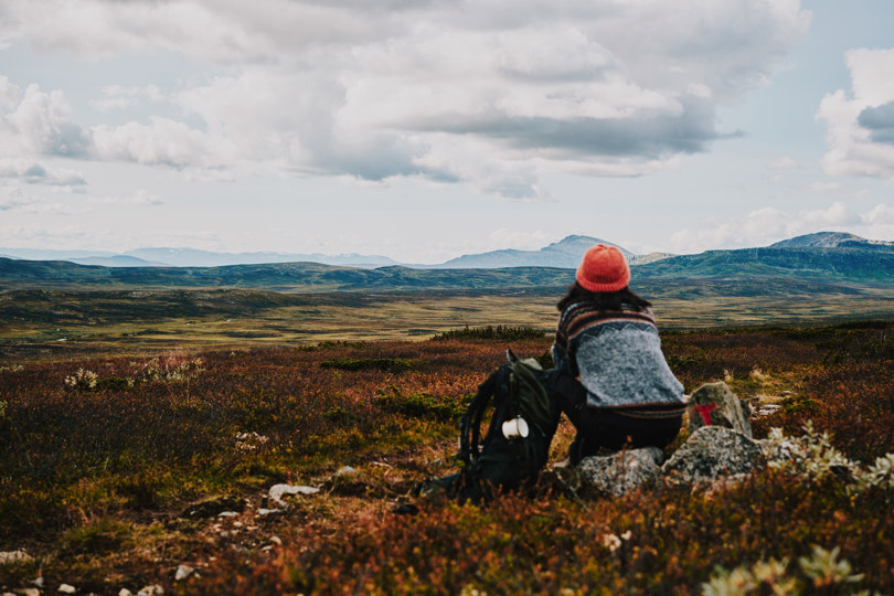 Menneske sitter og ser utover fjellandskap.