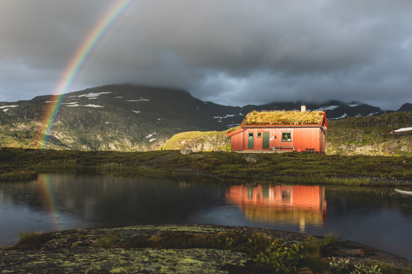 Rød hytte under regnbue.