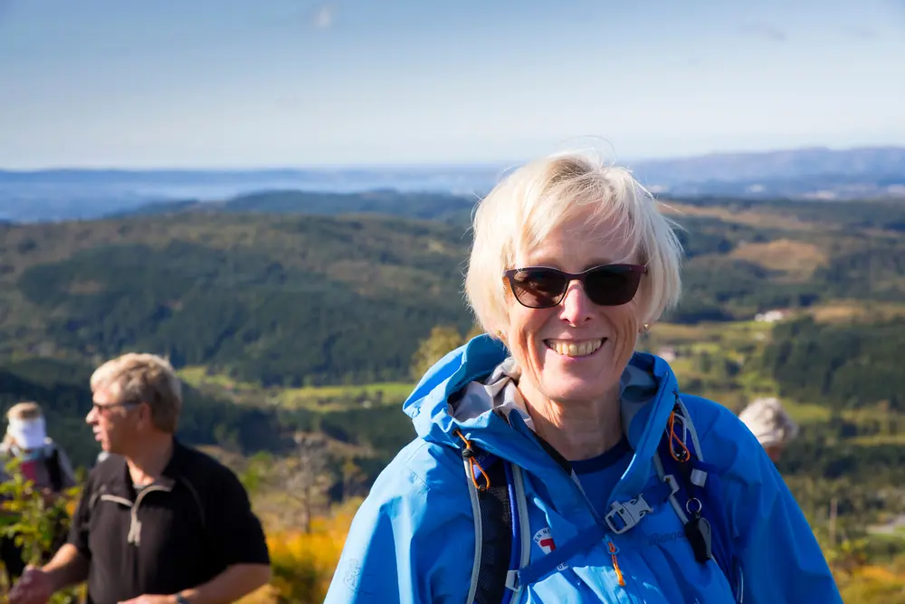 Kvinne på tur. Har på solbriller. Smiler. Foto 