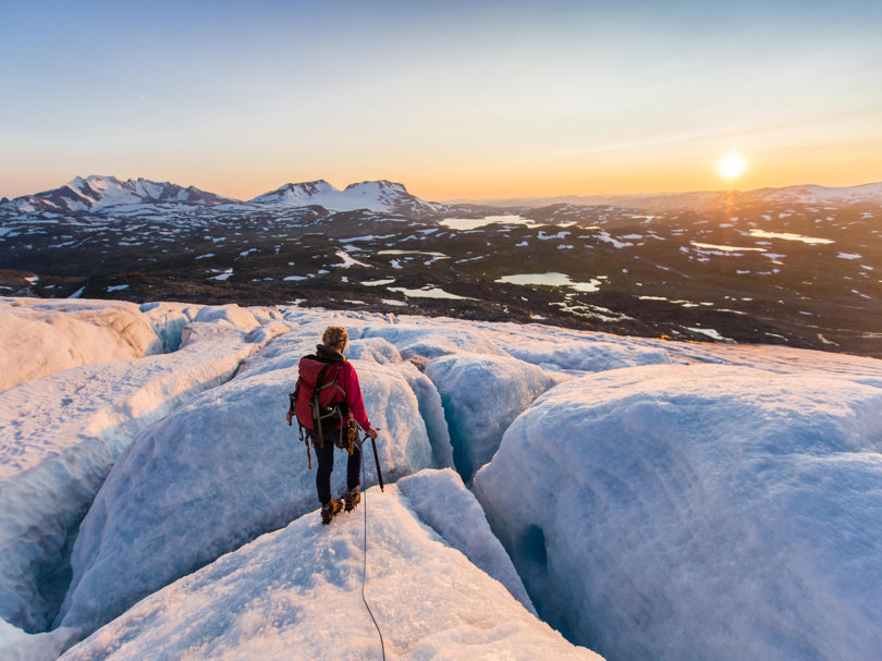 Menneske i solnedgang på isbre. Foto.