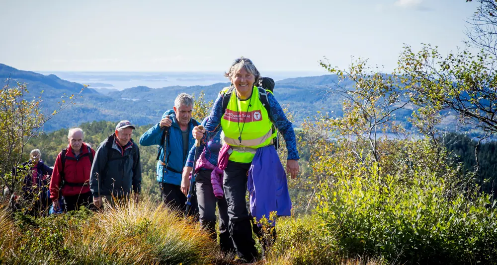 Turgruppe med turleder først. Høsttur med sol i fjellet. Foto