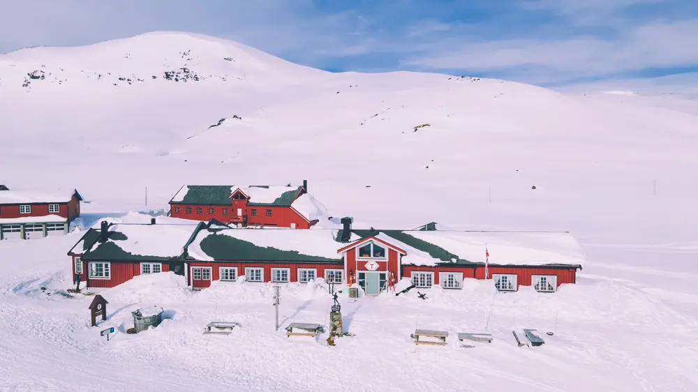 Rød hytte i vinterfjellet.