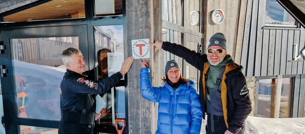 Inne i den lyse og levende resepsjonen på Leirvassbu står det en person bak skranken.