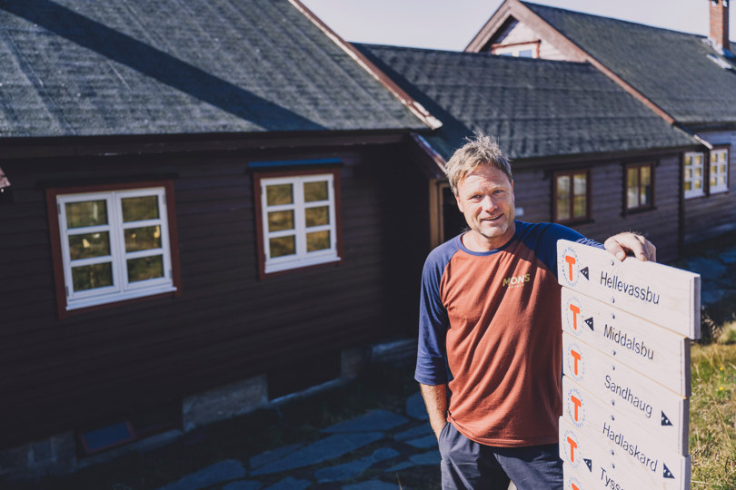 Bestyrer Jarle Viskje lener seg på et DNT-skilt utenfor Litloshytta. 
