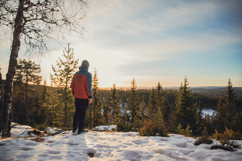 En mann som står og ser utover skogen