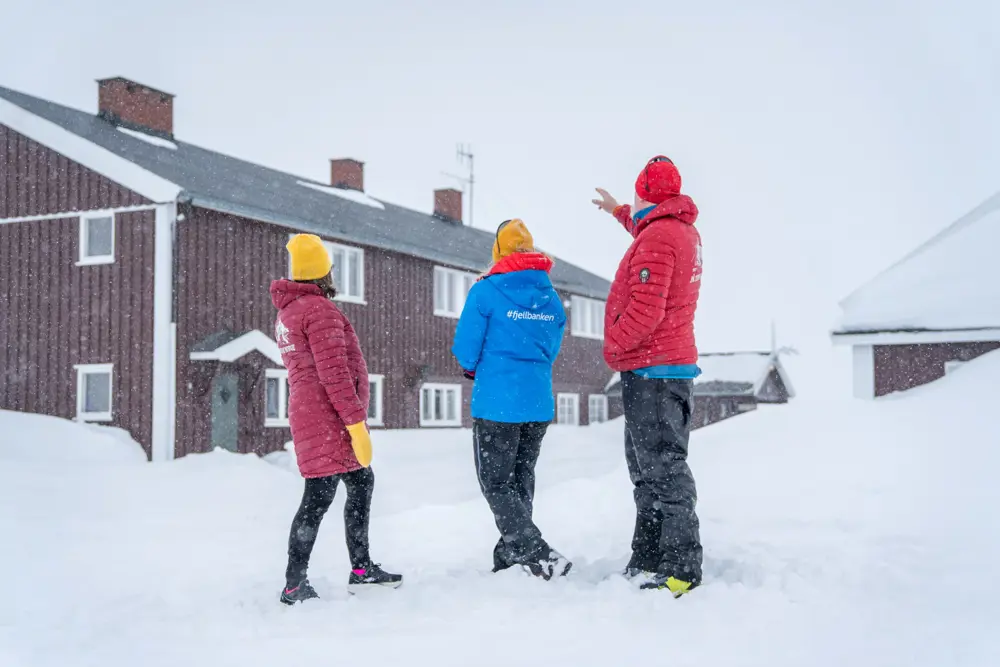 Bilde av tre personer som står foran DNT hytta Glitterheim. Vinteren 2023.