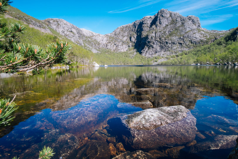 Blikkstille tjern innerst i en dal, med høye fjell rundt.