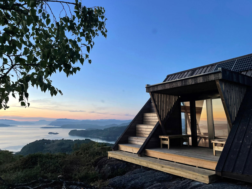 Solnedgang fra en fjelltopp med en dagsturhytte liggende i front av bildene. Utsikten viser flere øyer og holmer som ligger tett i tett i skjærgården  Ryfylke.