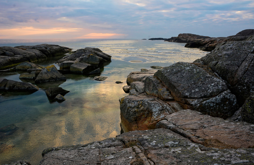 Havet møter steinete kystlinje med vakkert lys.