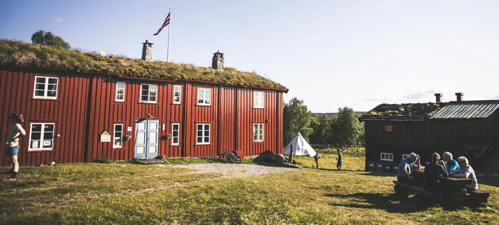 Dronebilde av hytta og gårdstunet i vinterlige forhold. 