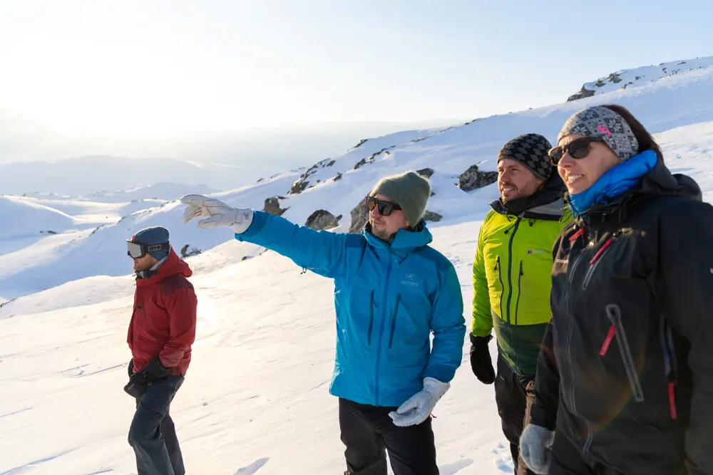 Fire personer kikker bort på noe i vinterlandskap.