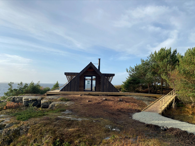 Dagsturhytte med havet bak. Foran hytta er det laget en lang trerampe og en grussti, slik at denne hytta er tilgjengelig for alle.
