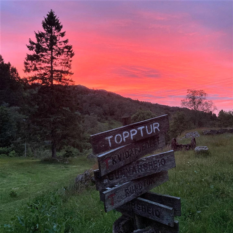 Rød solnedgang, nærbilde av treskilt.