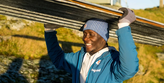 Dugnad og arbeidspraksis på Fjøløy turisthytte. John Magusi jobber med å rive taket på hytta.