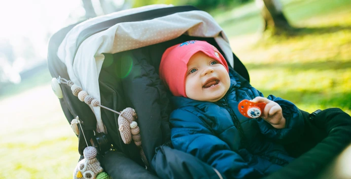 En baby sitter i en vogn og smiler bredt.