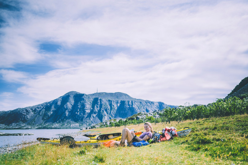 Dame foran telt, fjord og fjell