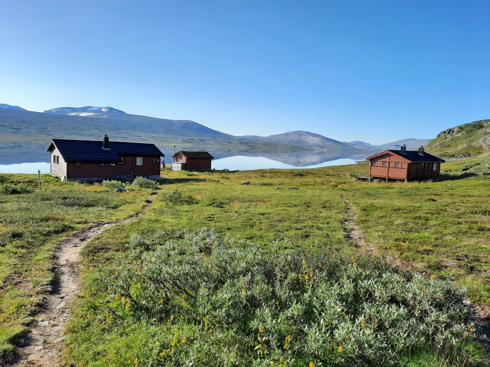 Begge hyttene ved Bjellåvasstua bader i sol en flott sommerdag.