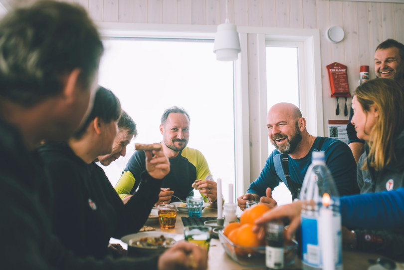 Flere personer sitter rundt et bord, spiser og har det hyggelig.