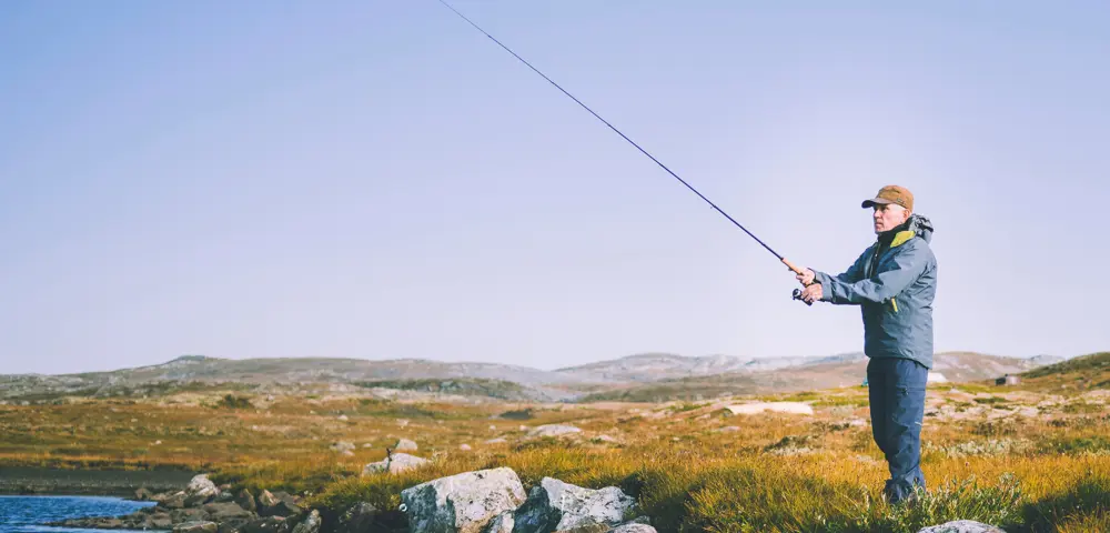 Reportasjetur over Hardangervidda i forbindele med jubileumsbok. Turgåer fisker ved vannet nedenfor Litlos turisthytte.