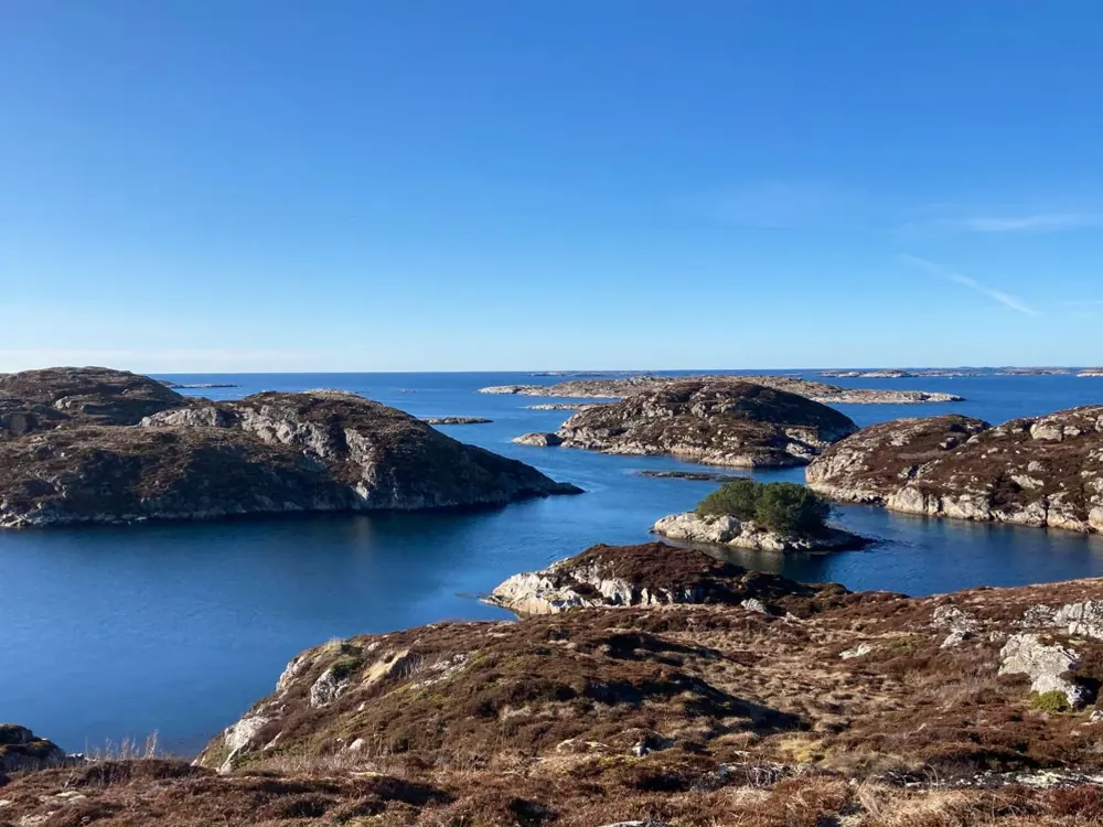 Bildet viser flere steinete svaberg som ligger rundt i havgapet foran oss, på en godværsdag. 