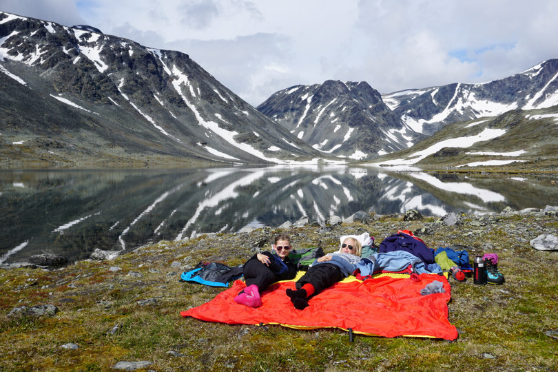 Barn ligger på tepper i fjellheimen. Fin utsikt. Foto.