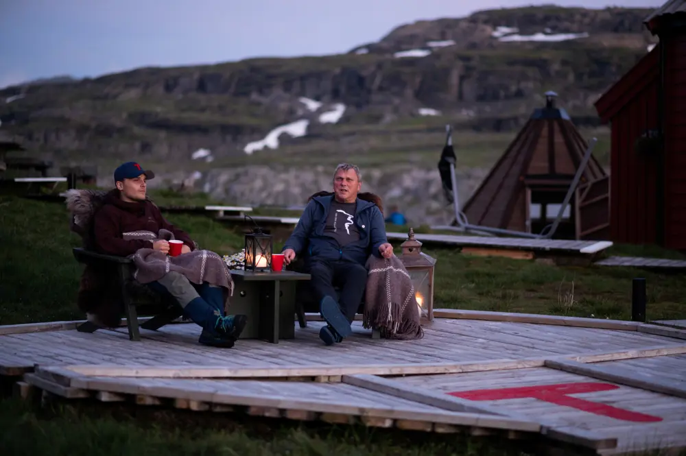 To menn sitter i hver sin stol utendørs i kveldsola.