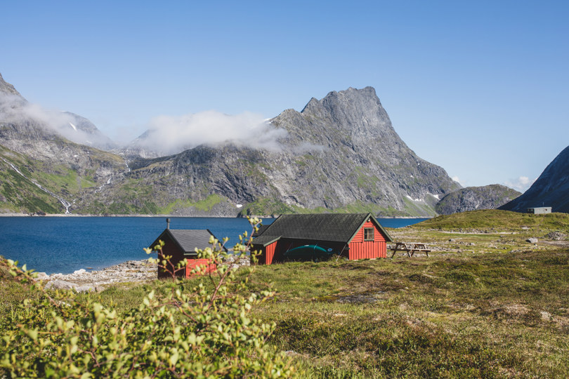 Rød hytte med fjell i bakgrunnen. 