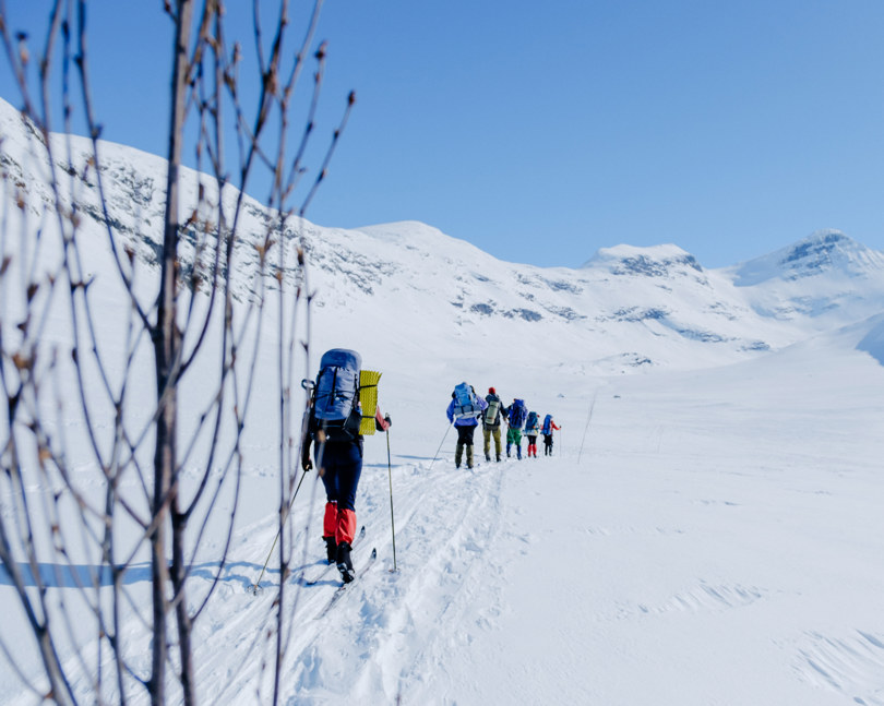 Flere personer på fjellski som går innover fjellet