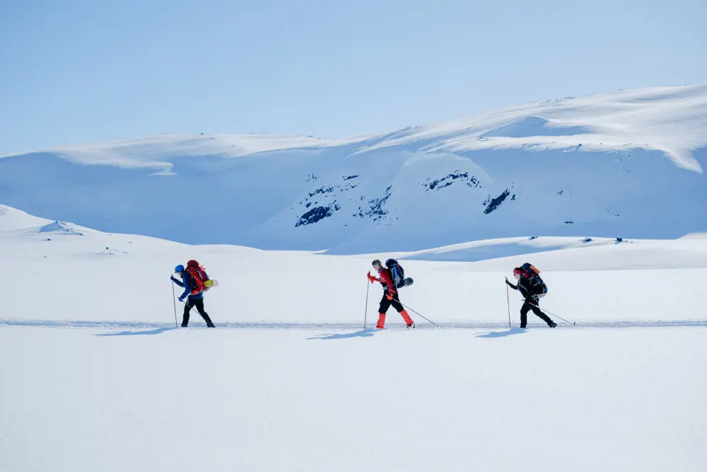 Tre skiløpere i vinterkledd fjellandskap