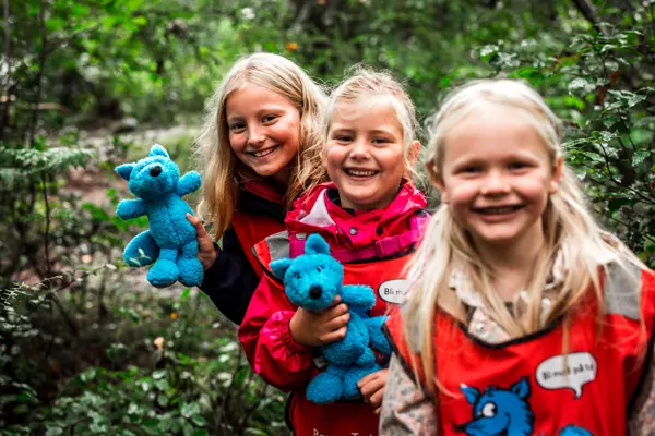 Tre jenter med lyst hår som ser i kamera og smiler. De holder hver sin turbobamse i hånden.