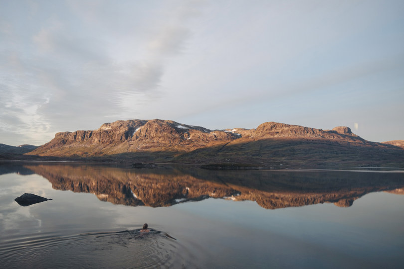En svømmer i det forfriskende vannet utenfor fjellstuen