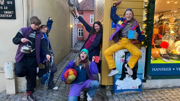 Fem ungdommer i brukte, kule klær jubler i et smau.