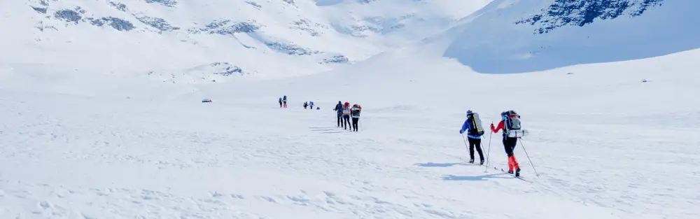 Personer som går på fjellski innover et vinterdekket fjellandskap