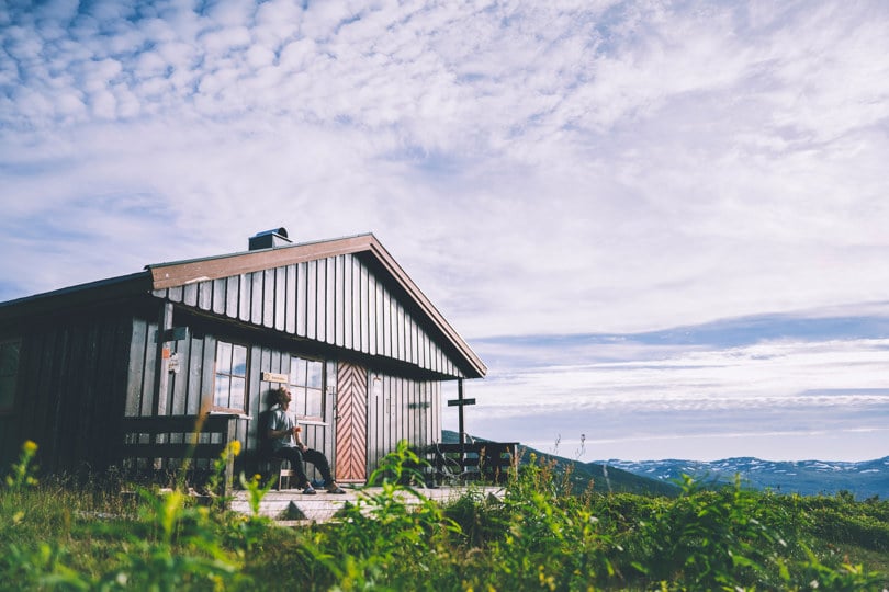 A man relaxing outside a DNT cabin