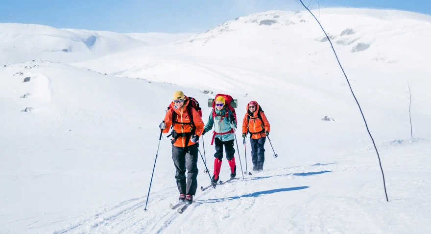Tre personer som går på fjellski innover vidda