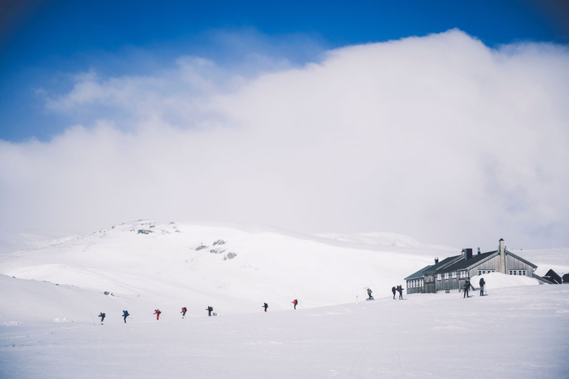 Flere personer som går ski frem til en hytte