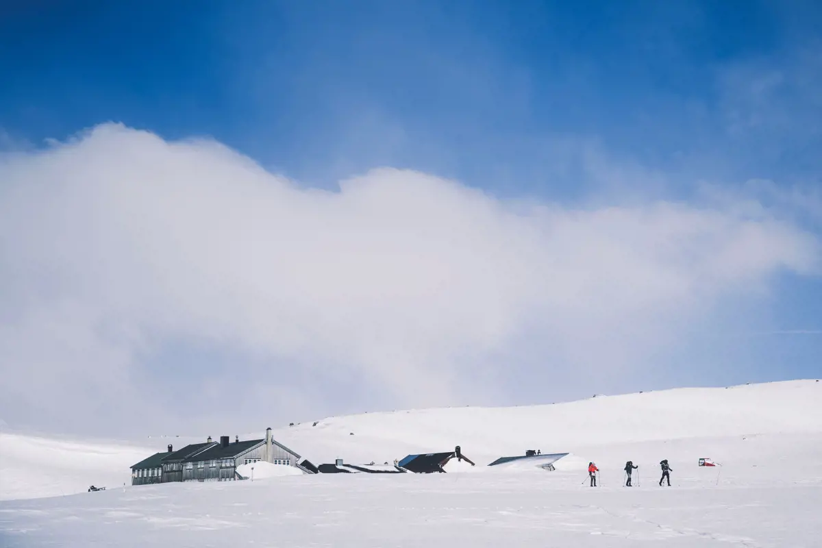 Tre personer som går på ski fra en hytte