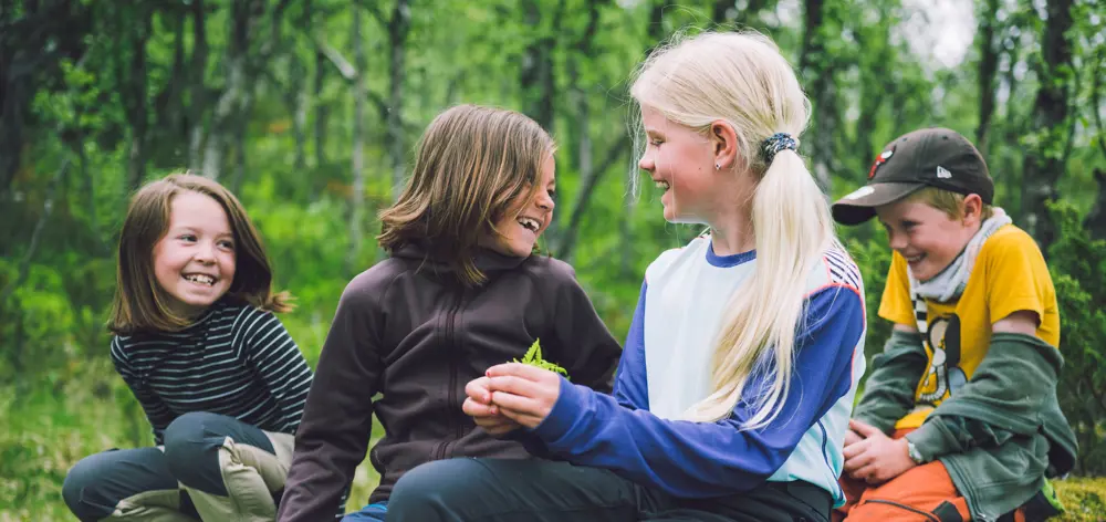 Fire barn som smiler og ler ute i skogen