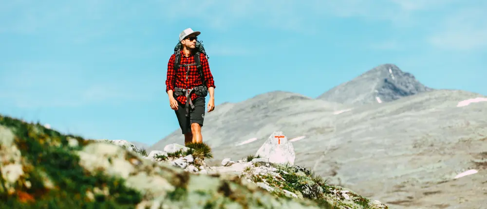 Mann i rød skjorte som går i fjellet