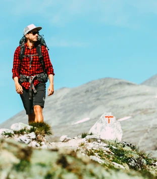 Mann i rød skjorte som går i fjellet