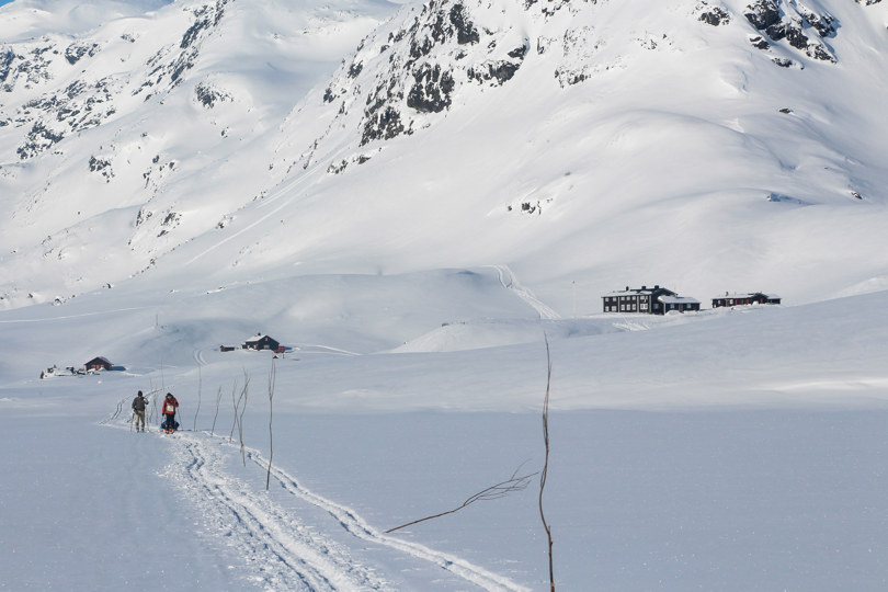 Tre personer som går på fjellski fra en hytte