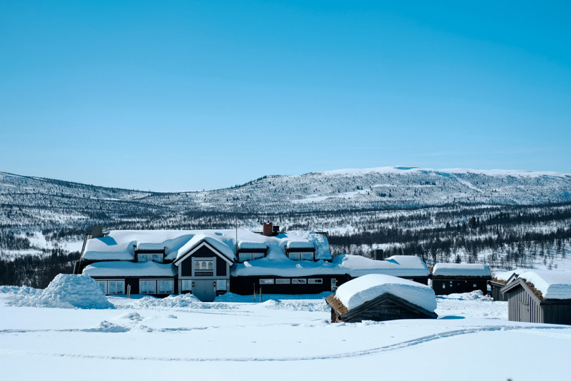 Svartmalt hytte med mye snø på taket