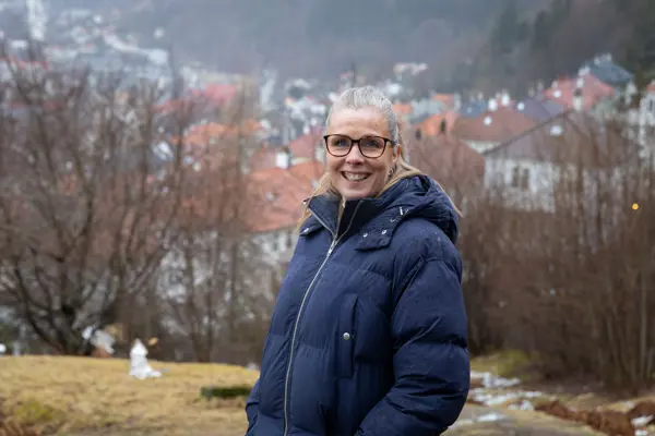 Kvinne med lyst hår i boblejakke smiler mot kamera.