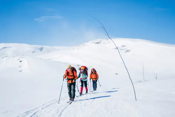 Tre personer går på ski