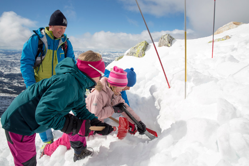Barn graver med spade i snøen etter påskeegg.