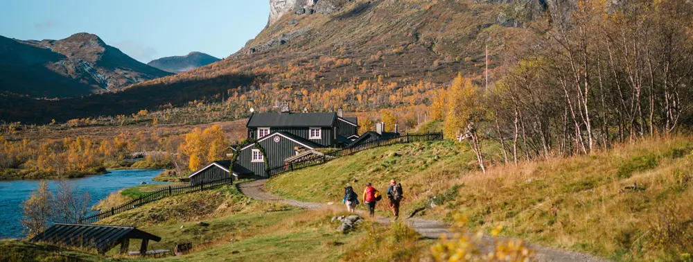 Personer som går til en hytte i fjellet