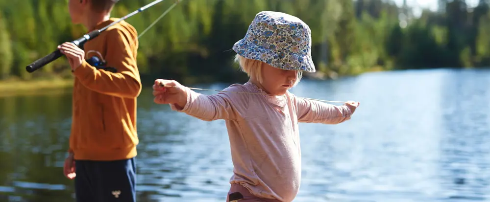 Barn med solhatt som balanserer på en stokk