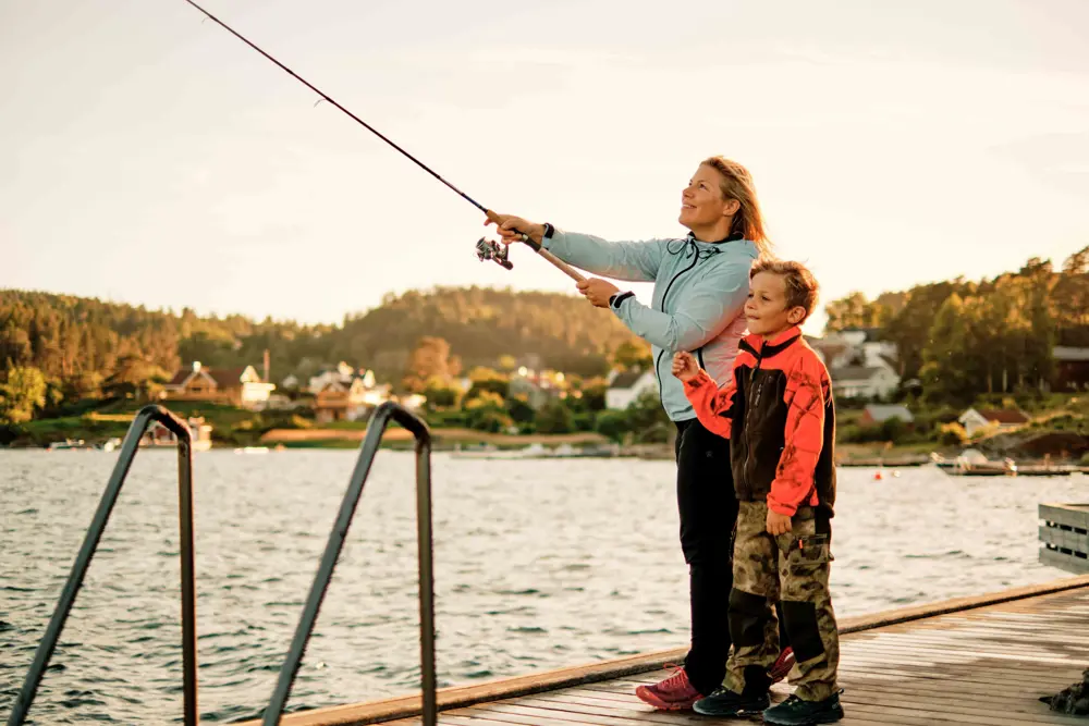 Dame og gutt fisker på brygge