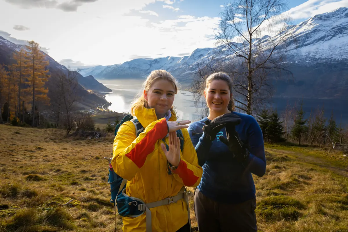 To jenter i Lofthus foran snøkledde vårfjell.